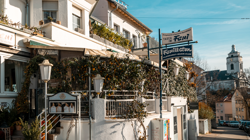 Ein Restaurant mit dem Namen 'Tasca im Feui', das portugiesische und spanische Spezialit&auml;ten anbietet. Daneben ein Schild f&uuml;r 'Feuilleton', einen Kleinkunst- und Musikclub., &copy; Stuttgart-Marketing GmbH, Sarah Schmid