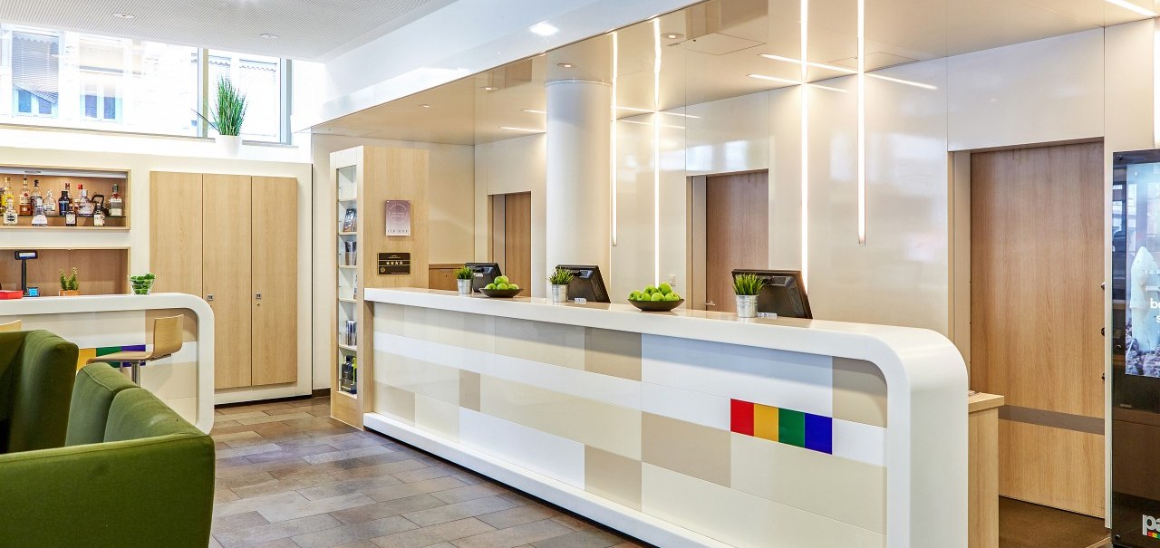 Moderne Lobby mit weißem Empfangstresen, grünen Sesseln und Barbereich. Helle Beleuchtung und dekorative Pflanzen schaffen eine einladende Atmosphäre., © Park Inn by Radisson Stuttgart Moderne Lobby mit weißem Empfangstresen, grünen Sesseln und Barbereich. Helle Beleuchtung und dekorative Pflanzen schaffen eine einladende Atmosphäre., © Park Inn by Radisson Stuttgart