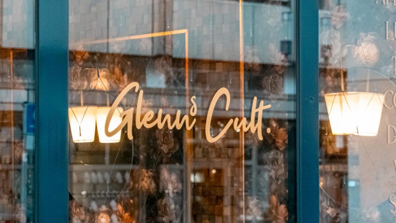 Fensterscheibe eines Caf&eacute;s mit dem Schriftzug 'Glenn's Cult' und Angeboten wie Aperitivo, Lunch, Tapas, Coffee, Drinks, Vino, Spirits., &copy; SMG, Sarah Schmid