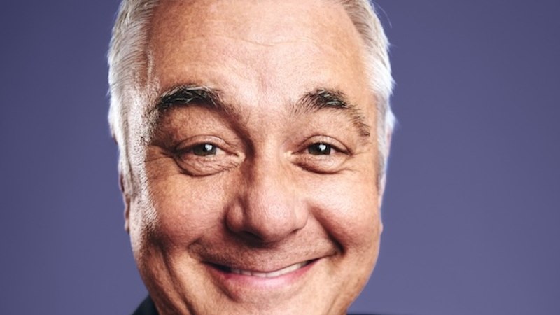 Ein Mann mit grauen Haaren l&auml;chelt in die Kamera. Er tr&auml;gt ein dunkles Oberteil. Der Hintergrund ist lila., &copy; Renitenztheater Stuttgart e.V.