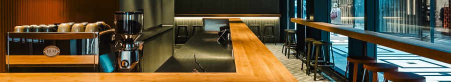 Modern bar with wooden counter, stools and stylish lighting in the Shobu Calwer Passage. Dark walls and geometric ceiling patterns., &copy; Blackbook Studios