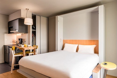Modern studio with large bed, small kitchen and dining table. Bright, minimalist furnishings with wood and gray tones., &copy; adagio access Stuttgart Airport Messe