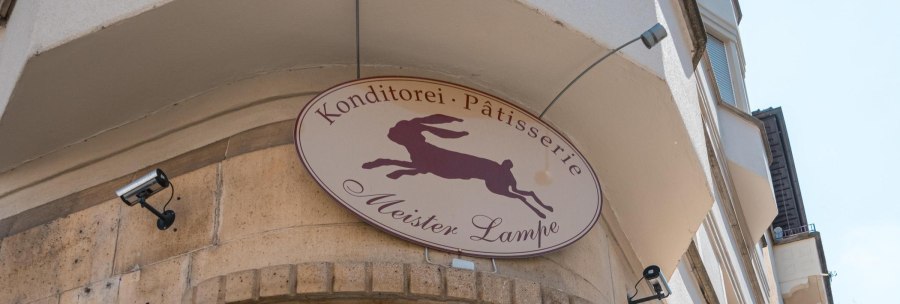Schild der Konditorei 'Meister Lampe' mit springendem Hasen, an einer Geb&auml;udefassade montiert., &copy; SMG, Sarah Schmid