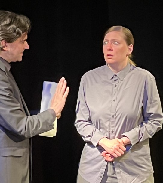 Zwei Personen in einem Theaterstück. Eine Person spricht gestikulierend, die andere schaut ernst. Dunkler Hintergrund., © Theater Atelier Zwei Personen in einem Theaterstück. Eine Person spricht gestikulierend, die andere schaut ernst. Dunkler Hintergrund., © Theater Atelier