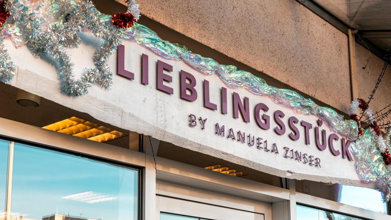 Schriftzug in roten Lettern auf weißem Grund: "Lieblingsstück by Manuela Zinser", zwei große Schaufenster befinden sich links und rechts der Eingangstür., © Stuttgart-Marketing GmbH, Sarah Schmid Schriftzug in roten Lettern auf weißem Grund: "Lieblingsstück by Manuela Zinser", zwei große Schaufenster befinden sich links und rechts der Eingangstür., © Stuttgart-Marketing GmbH, Sarah Schmid
