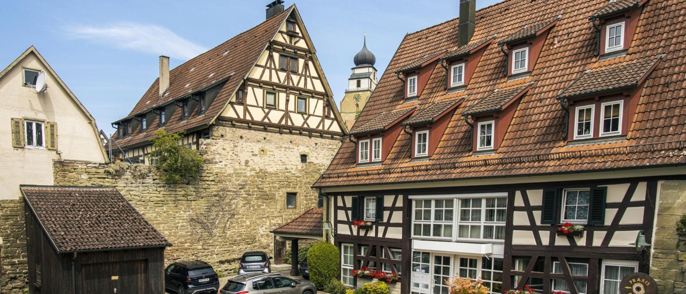 Half-timbered houses in the old town of Herrenberg, Germany. A church tower can be seen in the background. The buildings have red-tiled roofs and flower boxes in full bloom., © SMG Stuttgart Marketing GmbH - Sarah Schmid Half-timbered houses in the old town of Herrenberg, Germany. A church tower can be seen in the background. The buildings have red-tiled roofs and flower boxes in full bloom., © SMG Stuttgart Marketing GmbH - Sarah Schmid