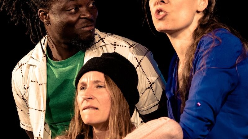 Drei Personen auf einer Bühne. Eine Frau in Blau spricht leidenschaftlich, während ein Mann und eine Frau mit Mütze aufmerksam zuhören., © Wilhelma Theater Drei Personen auf einer Bühne. Eine Frau in Blau spricht leidenschaftlich, während ein Mann und eine Frau mit Mütze aufmerksam zuhören., © Wilhelma Theater