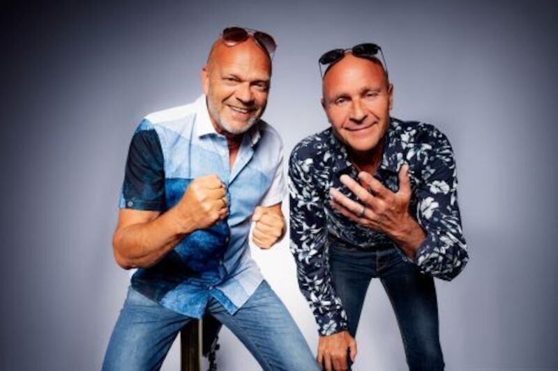 Zwei Männer in lässiger Kleidung posieren fröhlich vor einem neutralen Hintergrund. Beide tragen Sonnenbrillen auf dem Kopf., © Theaterhaus Stuttgart e.V. Zwei Männer in lässiger Kleidung posieren fröhlich vor einem neutralen Hintergrund. Beide tragen Sonnenbrillen auf dem Kopf., © Theaterhaus Stuttgart e.V.