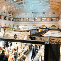 Blick von der Empore in die Stuttgarter Markthalle. Zahlreiche St&auml;nde und Besucher sind zu sehen, beleuchtet von hellem Licht., &copy; Stuttgart Marketing GmbH, Sarah Schmid