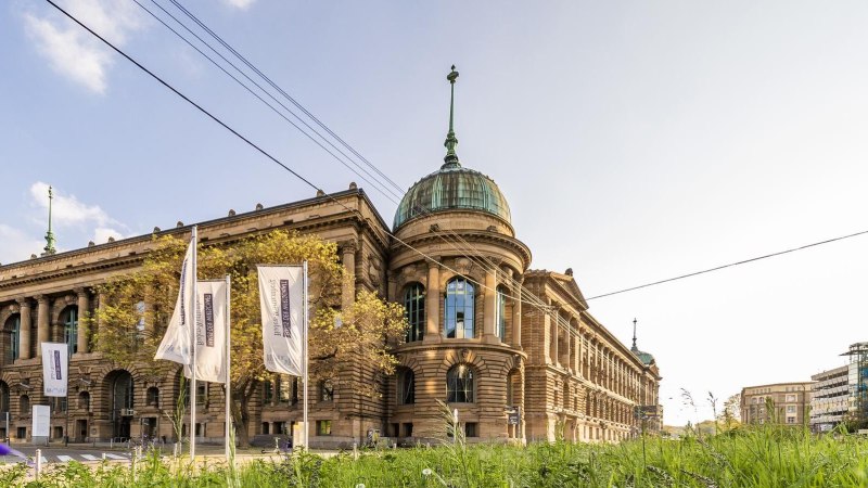 The Haus der Wirtschaft in Stuttgart with its magnificent fa&ccedil;ade and dome, surrounded by flags and green vegetation., &copy; &copy; Stuttgart-Marketing GmbH, Werner Dieterich