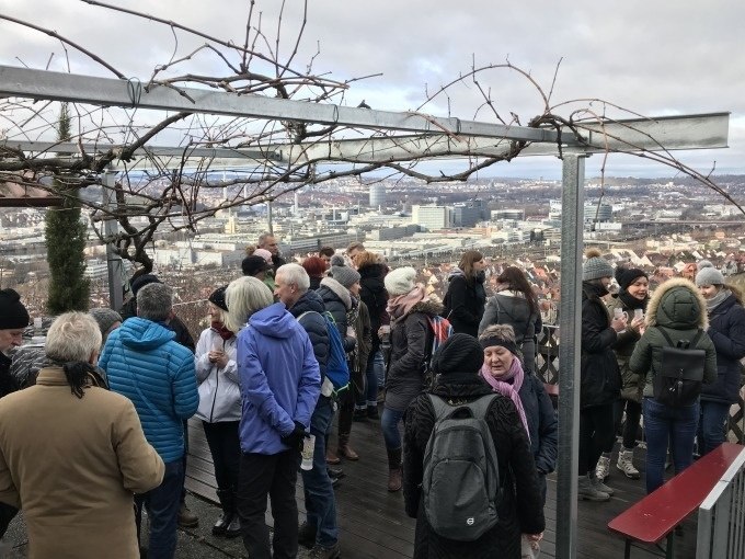Menschen bei einer Gl&uuml;hweinwanderung in Stuttgart, mit Blick auf die Stadt. Sie stehen unter einer Pergola und unterhalten sich., &copy; Weingenuss Stuttgart