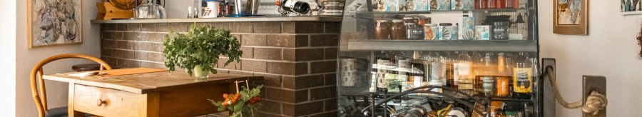 Gem&uuml;tliches Caf&eacute; mit Holztisch, Weinregal, dekorativen Bildern und Pflanzen. Eine Theke mit Getr&auml;nken und ein Fernseher sind ebenfalls zu sehen., &copy; SMG, Sarah Schmid