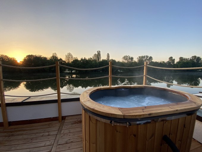 Holz-Whirlpool auf Terrasse mit Blick auf ruhigen Fluss und Bäume im Sonnenuntergang., © Cool-Tours StattReisen Holz-Whirlpool auf Terrasse mit Blick auf ruhigen Fluss und Bäume im Sonnenuntergang., © Cool-Tours StattReisen