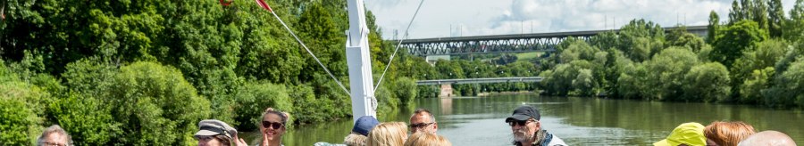 Menschen genie&szlig;en eine Bootsfahrt auf dem Neckar. Sie sitzen auf dem Deck, umgeben von gr&uuml;ner Landschaft und unterhalten sich fr&ouml;hlich., &copy; all copyrights are reserved by maks richter