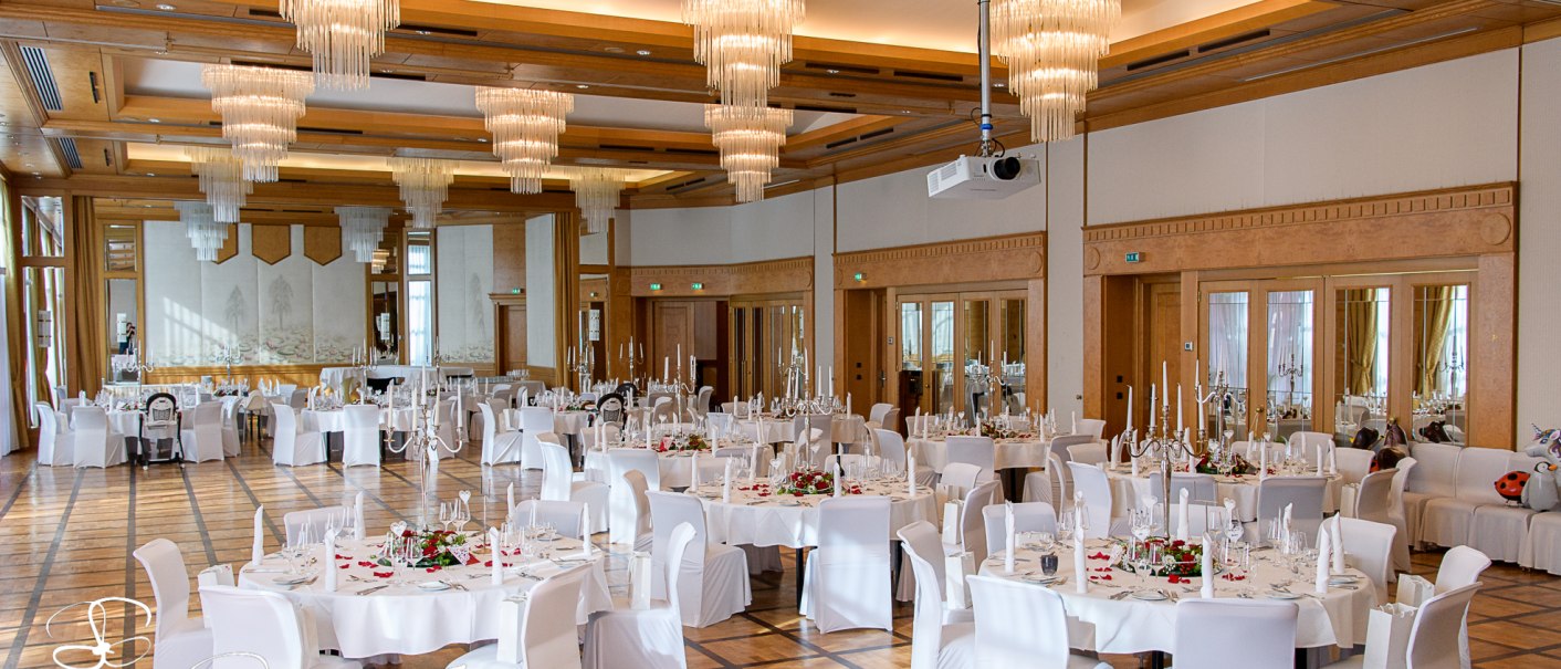 Eleganter Bankettsaal mit runden, weiß gedeckten Tischen, weißen Stühlen und beeindruckenden Kronleuchtern an der Decke., © Pullman Stuttgart Fontana
