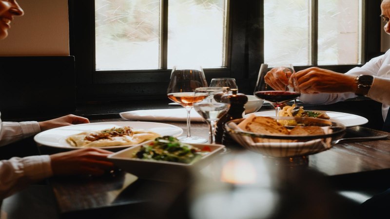 Two people are enjoying a meal in a restaurant. There is wine, bread and salad on the table. The atmosphere is cozy and elegant., © © Stuttgart-Marketing GmbH, Alwin Maigler