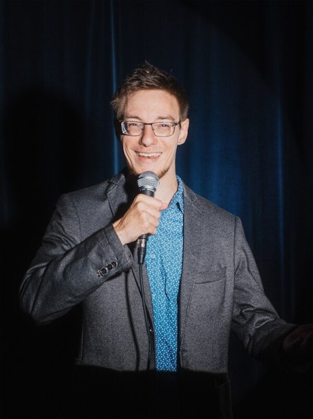 Ein Mann mit Brille und Mikrofon steht lächelnd vor einem blauen Vorhang. Er trägt ein graues Sakko und ein blaues Hemd., © Rosenau Kultur e.V. Ein Mann mit Brille und Mikrofon steht lächelnd vor einem blauen Vorhang. Er trägt ein graues Sakko und ein blaues Hemd., © Rosenau Kultur e.V.