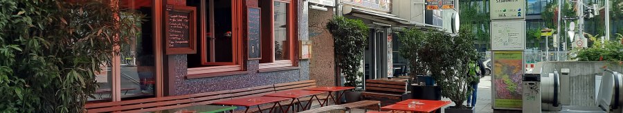 Außenbereich eines Cafés namens Mos Eisley mit bunten Tischen und Bänken. Daneben ein S- und U-Bahn-Schild am Rotebühlplatz Stadtmitte., © SMG