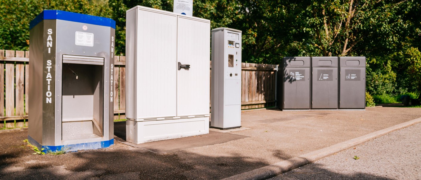 Sanistation und Müllcontainer auf einem Wohnmobilstellplatz, umgeben von Bäumen und einem Holzzaun., © Stuttgart-Marketing GmbH, Thomas Niedermüller Sanistation und Müllcontainer auf einem Wohnmobilstellplatz, umgeben von Bäumen und einem Holzzaun., © Stuttgart-Marketing GmbH, Thomas Niedermüller