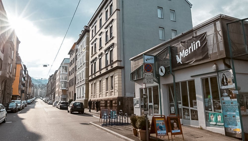 Street scene in Stuttgart with the cultural center Merlin e.V. on the right. The sun is shining, cars are parked along the street., © Merlin, Stuttgart Street scene in Stuttgart with the cultural center Merlin e.V. on the right. The sun is shining, cars are parked along the street., © Merlin, Stuttgart