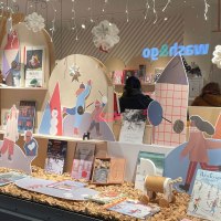 Ein Schaufenster mit winterlicher Dekoration, Kinderbüchern und Pappfiguren. Lichterketten und Schneeflocken hängen von der Decke., © Stuttgart-Marketing GmbH