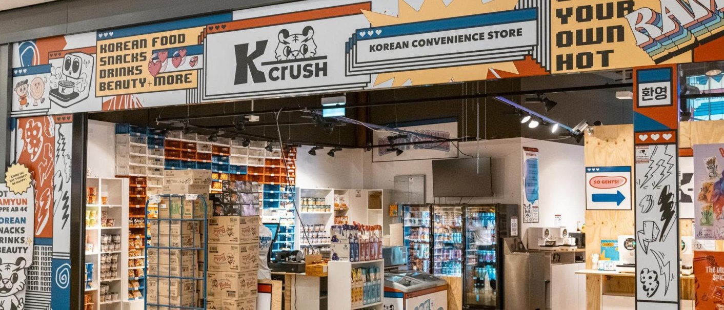 Eingang eines koreanischen Convenience Stores namens K-Crush mit bunten Schildern und Regalen voller Snacks und Getränke., © Stuttgart Marketing GmbH, Sarah Schmid