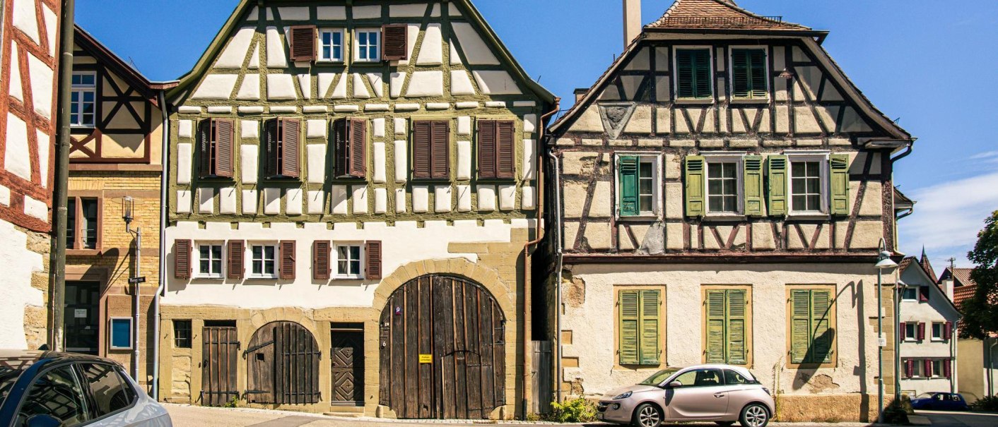 Two historic half-timbered houses in Vaihingen an der Enz, with colorful shutters and a car in the foreground, in bright sunshine., © Stuttgart-Marketing GmbH, Sarah Schmid Two historic half-timbered houses in Vaihingen an der Enz, with colorful shutters and a car in the foreground, in bright sunshine., © Stuttgart-Marketing GmbH, Sarah Schmid