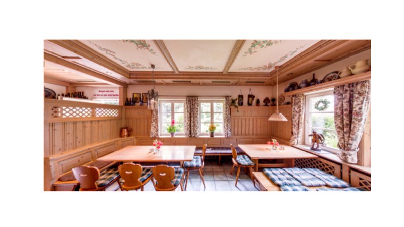 A cozy dining room with wooden furniture, checkered seat cushions and floral curtains. There are floral patterns on the ceiling and ceramics on shelves., &copy; Weingut Karl W&ouml;hrwag