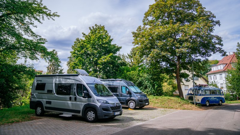 Wohnmobilstellplatz mit mehreren geparkten Wohnmobilen, umgeben von Bäumen und einem Haus im Hintergrund., © Stuttgart-Marketing GmbH, Thomas Niedermüller