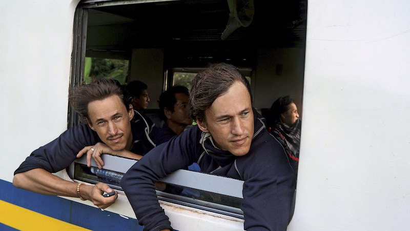 Two men lean out of a train window and look outside. Other passengers can be seen in the background., &copy; Theaterhaus Stuttgart e.V.