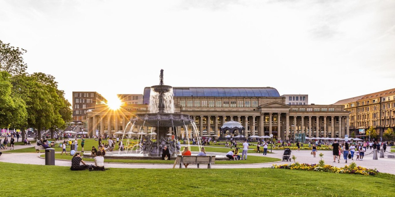 Schlossplatz in Stuttgart bei Sonnenuntergang, Menschen entspannen sich auf der Wiese, im Hintergrund der Königsbau und ein Brunnen., © Stuttgart-Marketing GmbH, Werner Dieterich Schlossplatz in Stuttgart bei Sonnenuntergang, Menschen entspannen sich auf der Wiese, im Hintergrund der Königsbau und ein Brunnen., © Stuttgart-Marketing GmbH, Werner Dieterich