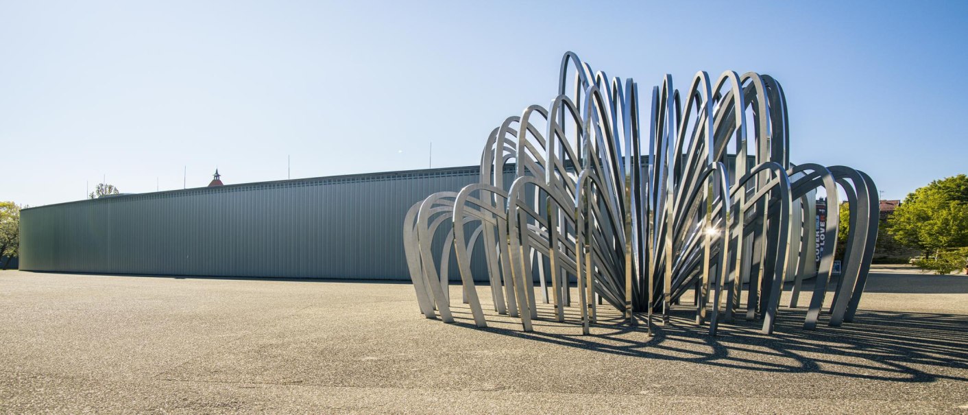 Moderne Skulptur aus gebogenen Metallstreben vor der Galerie Stihl in Waiblingen, bei klarem Himmel und Sonnenschein., © SMG, Sarah Schmid Moderne Skulptur aus gebogenen Metallstreben vor der Galerie Stihl in Waiblingen, bei klarem Himmel und Sonnenschein., © SMG, Sarah Schmid