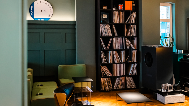 Stilvoller Raum mit Plattensammlung, Lautsprecher, gemütlichen Sesseln und einem Fenster. Ein Schild mit 'Blue Note' ist an der Wand., © Stuttgart-Marketing GmbH, Sarah Schmid