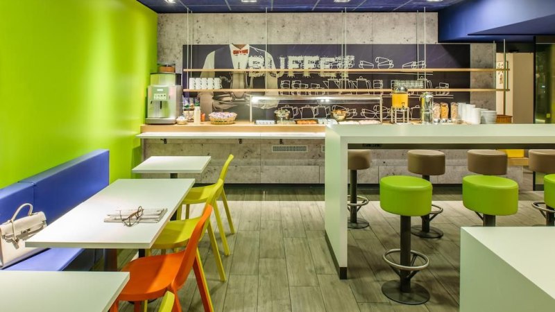 A modern breakfast buffet with colorful chairs, green walls and a selection of food and drinks., &copy; ibis budget Stuttgart City Nord