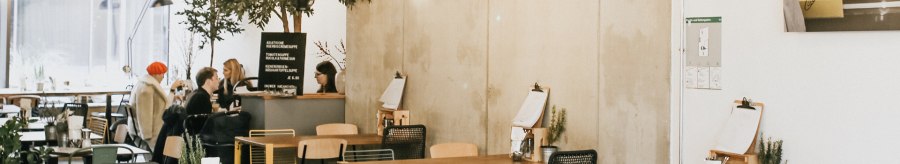Modern caf&eacute; with a hanging bicycle on the wall, plants and cozy seating areas. People sit and chat at tables., &copy; Claus Stuttgart