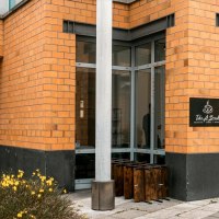 Eingang des Caf&eacute;s mit gelben Backsteinw&auml;nden. Gelbe Blumen im Vordergrund., &copy; Stuttgart-Marketing GmbH, Sarah Schmid
