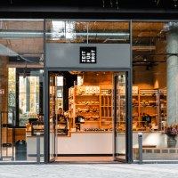 Entrance to a bakery with a glass front. Shelves with baked goods can be seen inside. 'Time for bread' is written above the door., &copy; Zeit f&uuml;r Brot Stuttgart