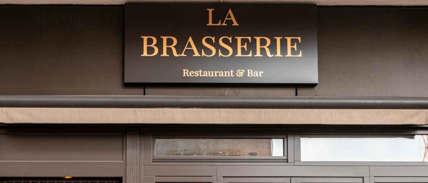Das Bild zeigt das Eingangsschild eines Restaurants mit der Aufschrift 'La Brasserie Restaurant & Bar'., &copy; SMG, Sarah Schmid
