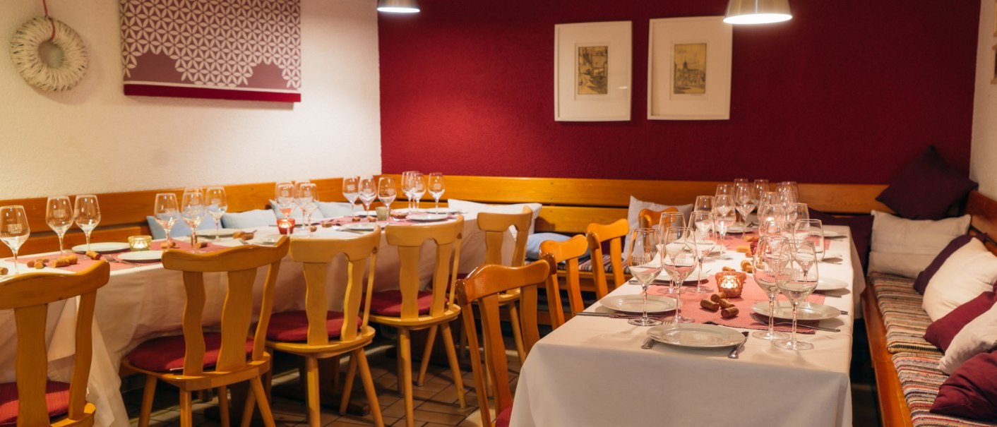 Comfortably laid table in a restaurant with wine glasses, candles and wooden furniture. The walls are decorated in red and white., &copy; 70469R! Weinbau Fabian Rajtschan