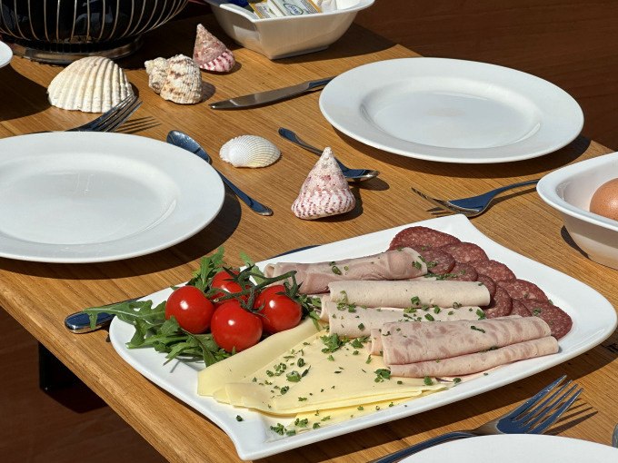 Ein gedeckter Frühstückstisch mit Wurst, Käse, Tomaten und Muscheln als Dekoration., © Cool-Tours StattReisen Ein gedeckter Frühstückstisch mit Wurst, Käse, Tomaten und Muscheln als Dekoration., © Cool-Tours StattReisen