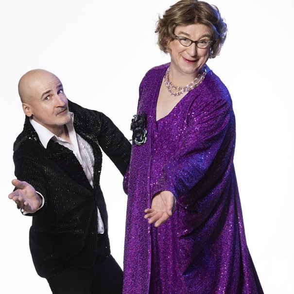 Ein humorvolles Duo posiert in auffälliger Kleidung. Der Mann trägt einen schwarzen Anzug, die andere Person ein lila Glitzerkleid., © Renitenztheater Stuttgart e.V. Ein humorvolles Duo posiert in auffälliger Kleidung. Der Mann trägt einen schwarzen Anzug, die andere Person ein lila Glitzerkleid., © Renitenztheater Stuttgart e.V.