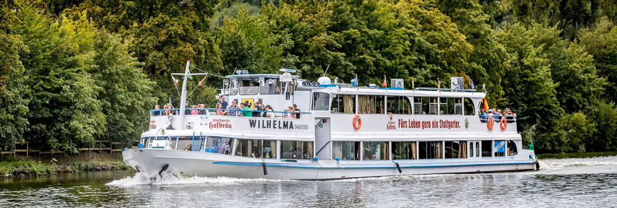 The excursion boat sails on a river surrounded by lush greenery. There are many passengers on board enjoying the view., &copy; NeckarFlair MS Wilhelma Betriebsgesellschaft mbH