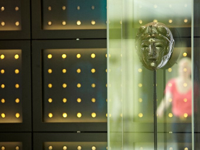 Antike Maske in einer Vitrine, beleuchtete Wand im Hintergrund. Eine Person ist unscharf im Hintergrund zu sehen., © Landesmuseum Württemberg Antike Maske in einer Vitrine, beleuchtete Wand im Hintergrund. Eine Person ist unscharf im Hintergrund zu sehen., © Landesmuseum Württemberg
