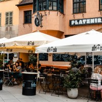 Außenbereich des Cafés Platzhirsch mit weißen Sonnenschirmen und Gästen an Tischen. Die Fassade ist orange, und es gibt Pflanzen als Dekoration., © SMG Stuttgart Marketing GmbH - Sarah Schmid Außenbereich des Cafés Platzhirsch mit weißen Sonnenschirmen und Gästen an Tischen. Die Fassade ist orange, und es gibt Pflanzen als Dekoration., © SMG Stuttgart Marketing GmbH - Sarah Schmid