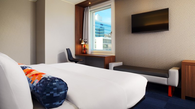Ein modernes Hotelzimmer mit einem großen Bett, einem Schreibtisch am Fenster und einem Flachbildfernseher an der Wand., © Aloft Stuttgart Ein modernes Hotelzimmer mit einem großen Bett, einem Schreibtisch am Fenster und einem Flachbildfernseher an der Wand., © Aloft Stuttgart