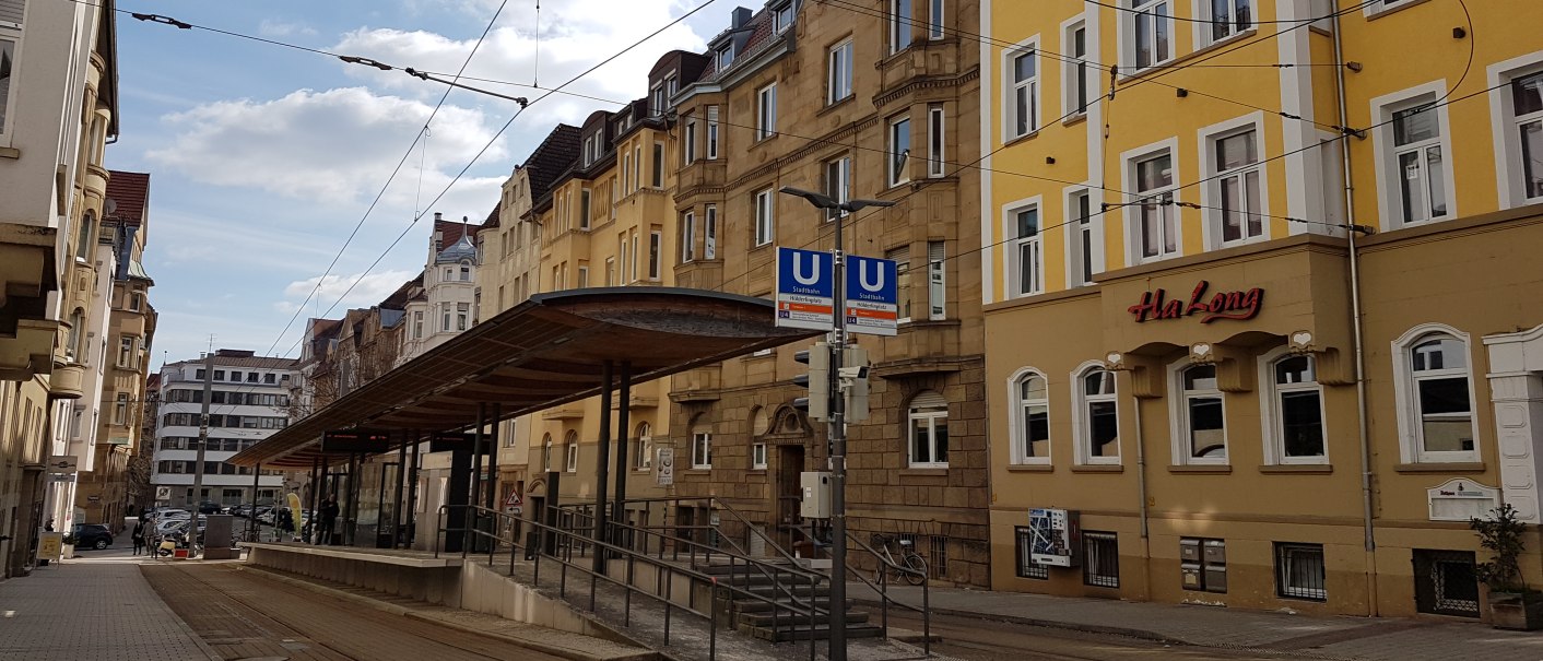 Straßenbahnhaltestelle in einer städtischen Straße, umgeben von alten Gebäuden. Ein Restaurant namens Ha Long ist zu sehen., © SMG Straßenbahnhaltestelle in einer städtischen Straße, umgeben von alten Gebäuden. Ein Restaurant namens Ha Long ist zu sehen., © SMG