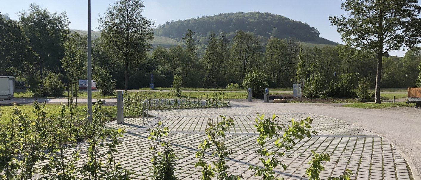 Wohnmobilstellplatz am Wunnebad mit gepflastertem Boden, umgeben von B&auml;umen und einem bewaldeten H&uuml;gel im Hintergrund., &copy; Stadtwerke Winnenden GmbH
