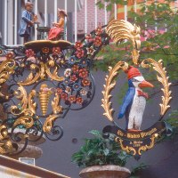 An artistically decorated sign with a penguin and figures, surrounded by floral ornaments, hangs on a wall on Eugensplatz., © Stuttgart-Marketing GmbH An artistically decorated sign with a penguin and figures, surrounded by floral ornaments, hangs on a wall on Eugensplatz., © Stuttgart-Marketing GmbH