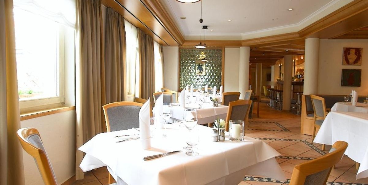 Ein elegantes Restaurant mit weißen Tischdecken, Holzstühlen und großen Fenstern. Die Einrichtung ist modern mit warmen Holztönen., © Hotel am Park Ein elegantes Restaurant mit weißen Tischdecken, Holzstühlen und großen Fenstern. Die Einrichtung ist modern mit warmen Holztönen., © Hotel am Park