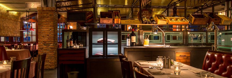 Stylish restaurant with brick walls, laid tables and wine racks. Warm light creates a cozy atmosphere., © Pier 51